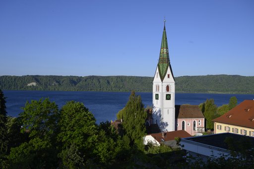 Ansicht Pfarrkirche mit Kirchturm. Im Hintergrund der See.