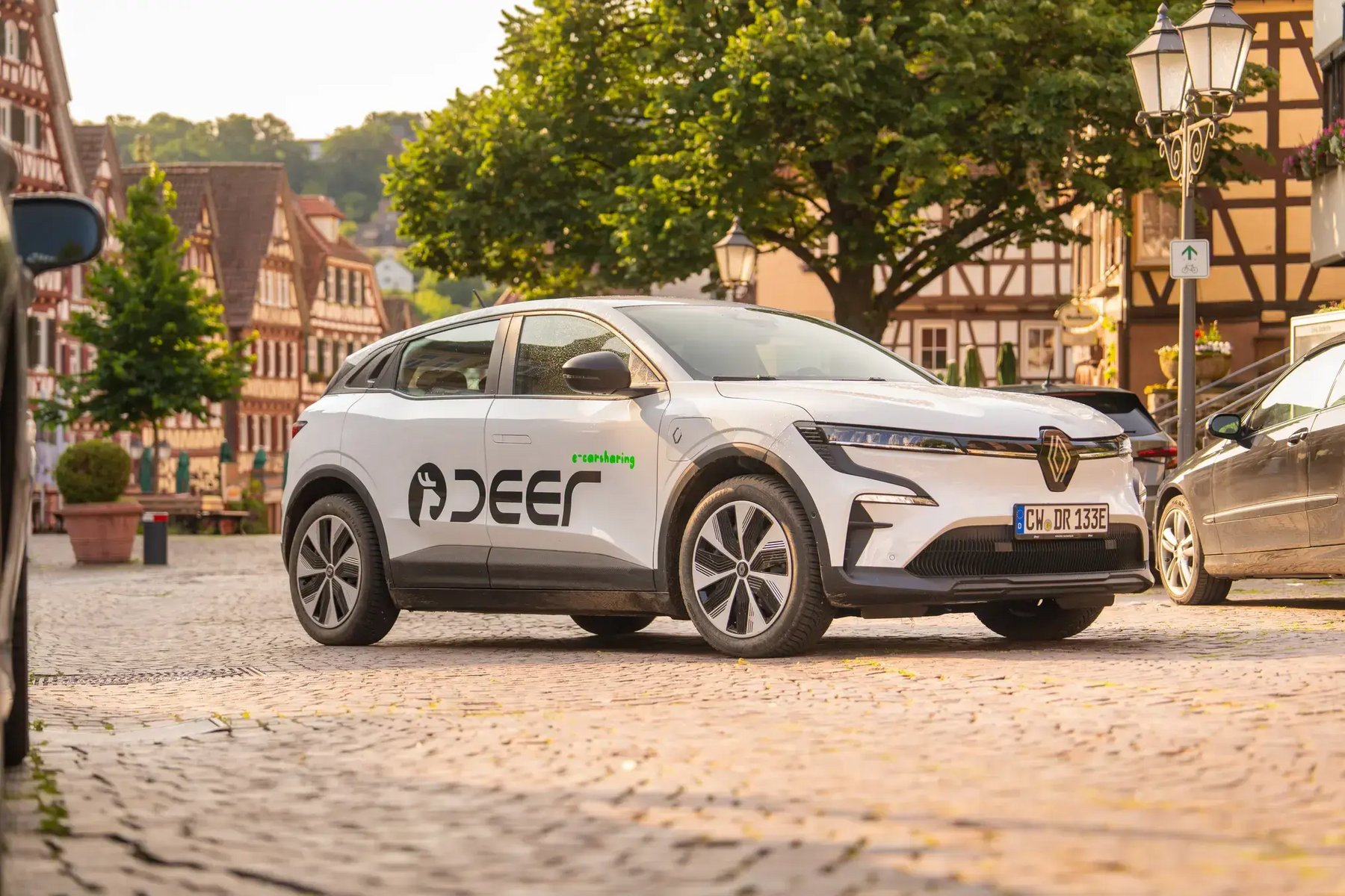 Ei weißes Auto der Firma deer parkt auf einer gepflasterten Straße