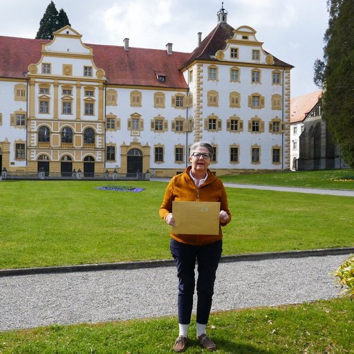 Elisabeth Lohrer, Ehrenamtliche Referentin für Geschichte und Dorfentwicklung der Gemeinde Sipplingen steht vor Schloss Salem und hölt einen Briefumschlag in der hand